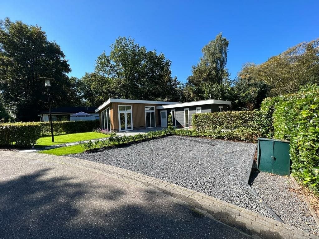 Moderne vakantiewoning met vlakke tuin, grindpad en omringende groenvoorziening in EuroParcs De Achterhoek.