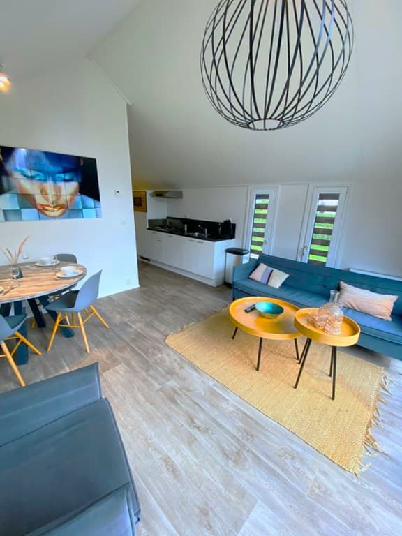 Moderne woonkamer met zithoek, eettafel en open keuken, grote ramen en kunst aan de muur