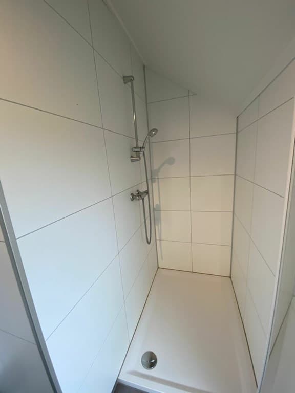 Moderne inloopdouche met witte wandtegels en metalen douchekop in EuroParcs Marina Strandbad, Olburgen