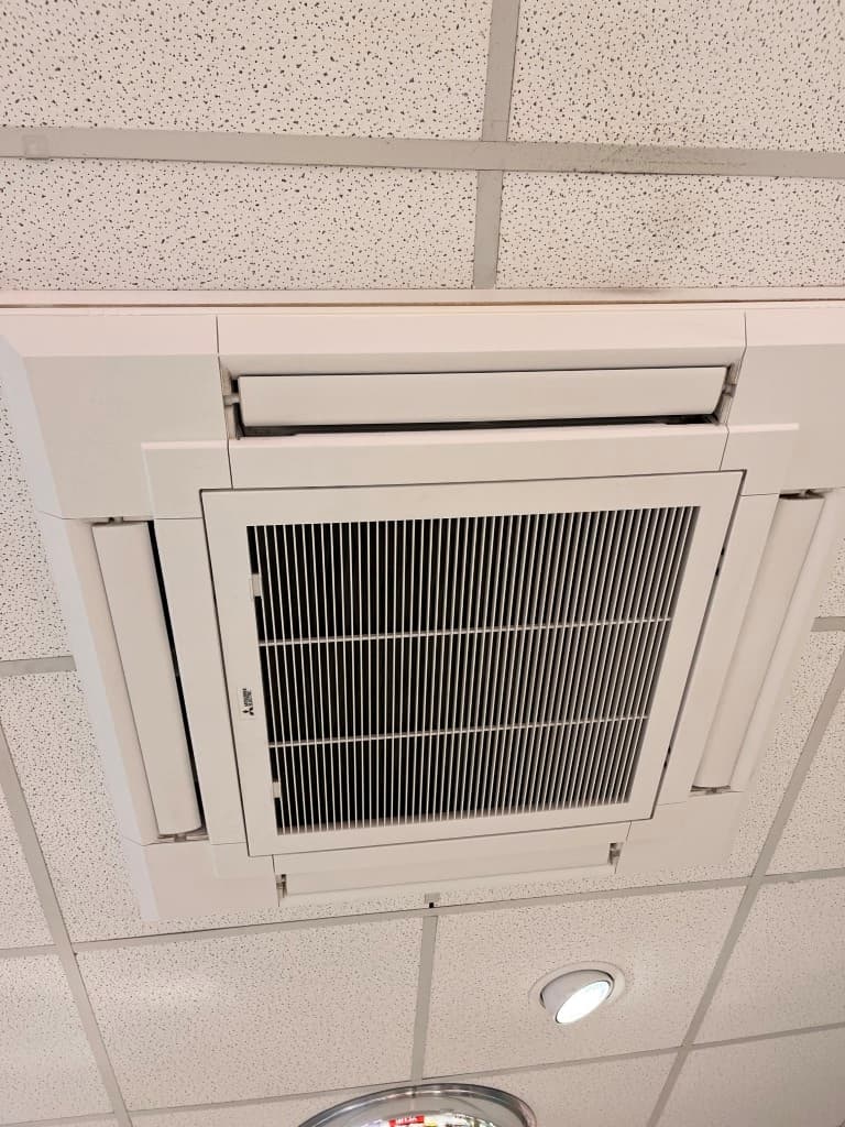 Verlicht plafond met een inbouw-airconditioningseenheid en perforaties voor luchtcirculatie.