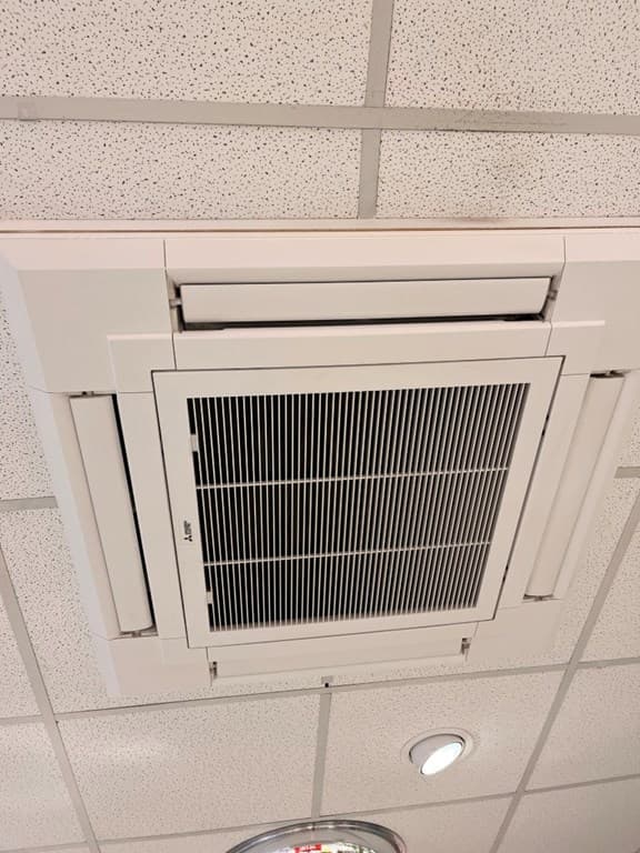 Verlicht plafond met een inbouw-airconditioningseenheid en perforaties voor luchtcirculatie.