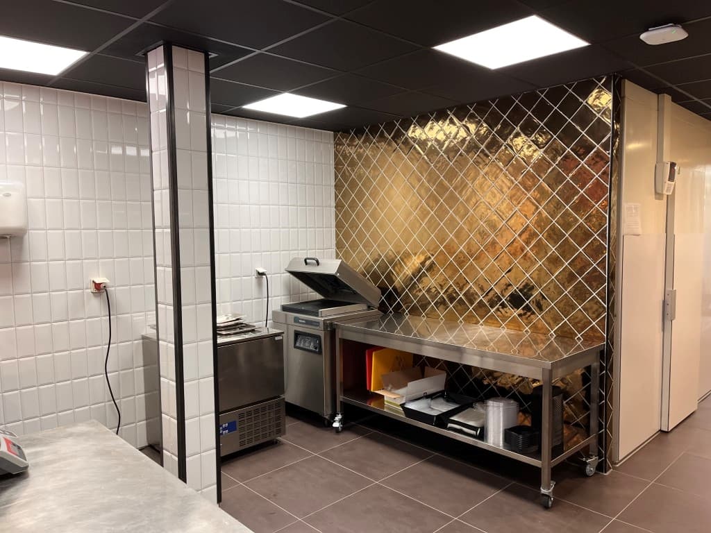 Moderne keuken met roestvrijstalen werkbladen, tegels en een gasfornuis met een afzuigkap.