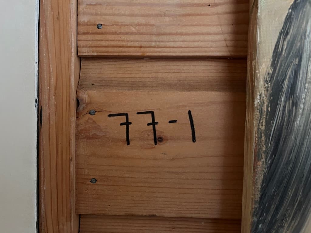 Houten wand met duidelijk zichtbaar nummer 77-1 geschreven in zwarte cijfers