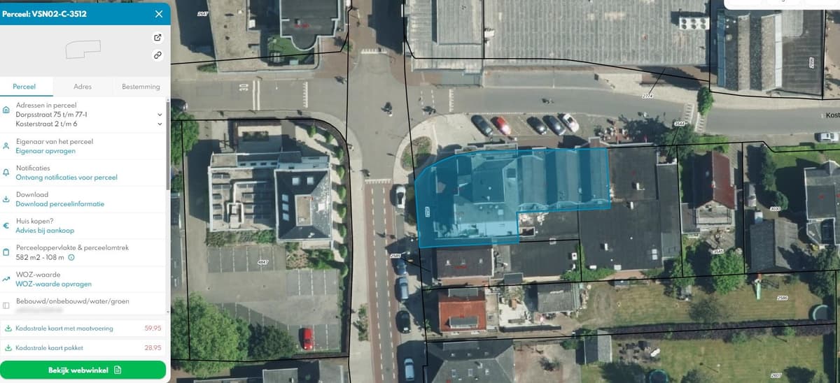 Bovenaanzicht van een appartement gelegen aan een kruising met omliggende gebouwen en aparte parkeerplaatsen.