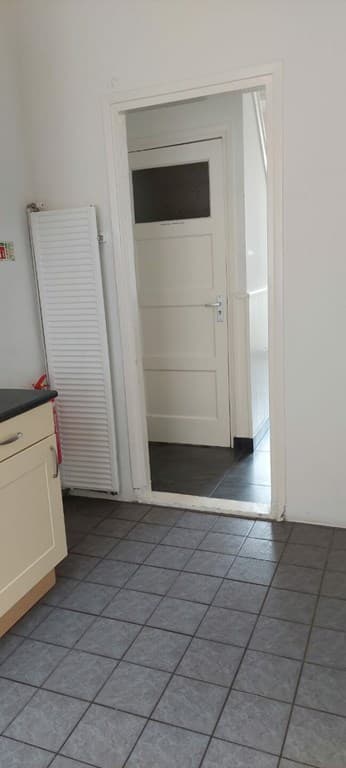 Uitzicht op een keuken met tegelvloer en een deur die naar een andere ruimte leidt.