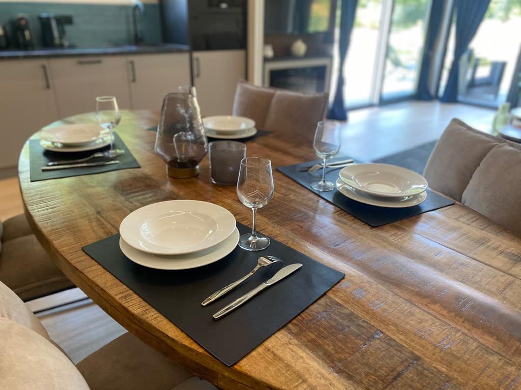 Eettafel met borden, glazen en bestek, omringd door stoelen in een lichte, moderne woning.