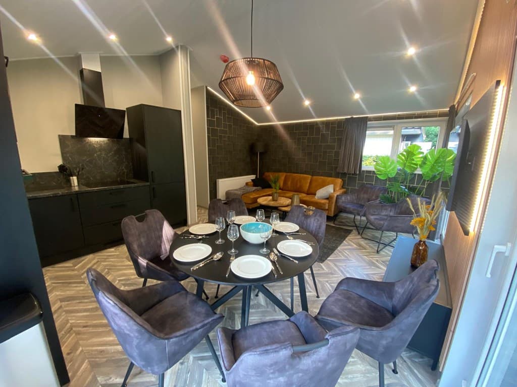 Eet- en woongedeelte met moderne meubels, een ronde eettafel en een gezellige zithoek met bank en planten.