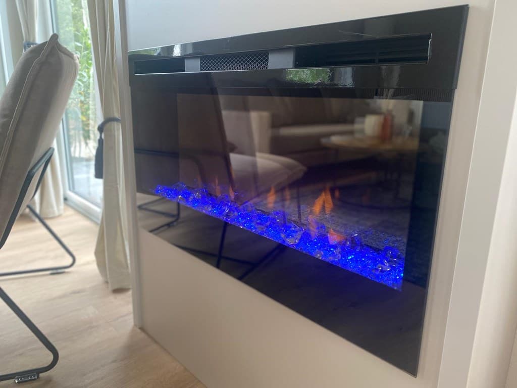 Moderne elektrische haard met blauwe verlichting in een lichte ruimte met veel natuurlijk licht en comfortabele meubels.