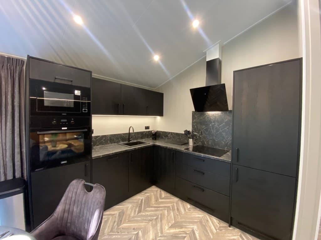 Moderne keuken met zwarte kasten, inbouwapparatuur en een marmeren werkblad in Residence Winterswijk.