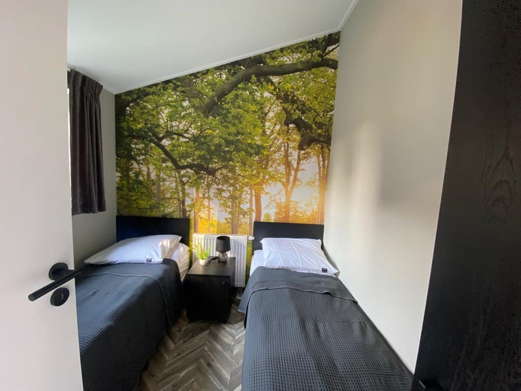 Slaapkamer met twee eenpersoonsbedden en een muurschildering van een boslandschap