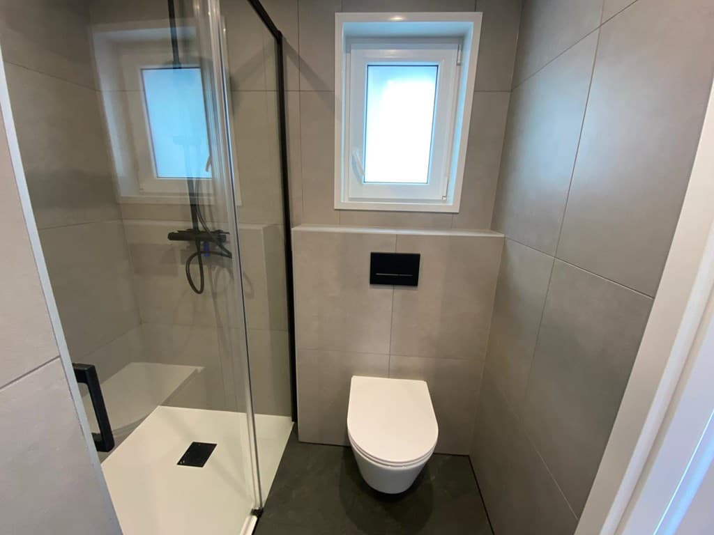 Moderne badkamer met een inloopdouche, wandcloset en een klein raam voor natuurlijk licht