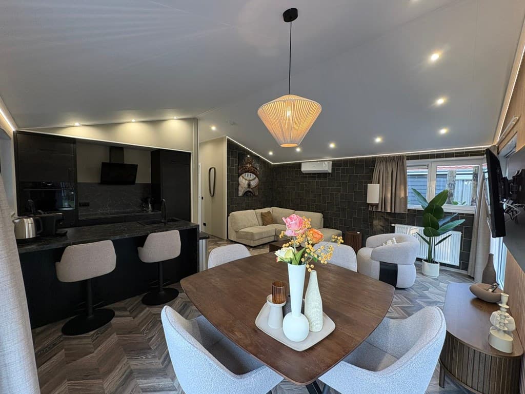 Moderne woonkamer met open keuken, eettafel, comfortabele bank en grote ramen voor natuurlijk licht