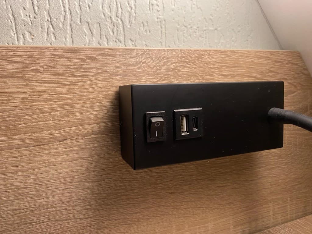 Inbouwpaneel met een aan/uit-schakelaar en USB-poort op een houten achterwand.