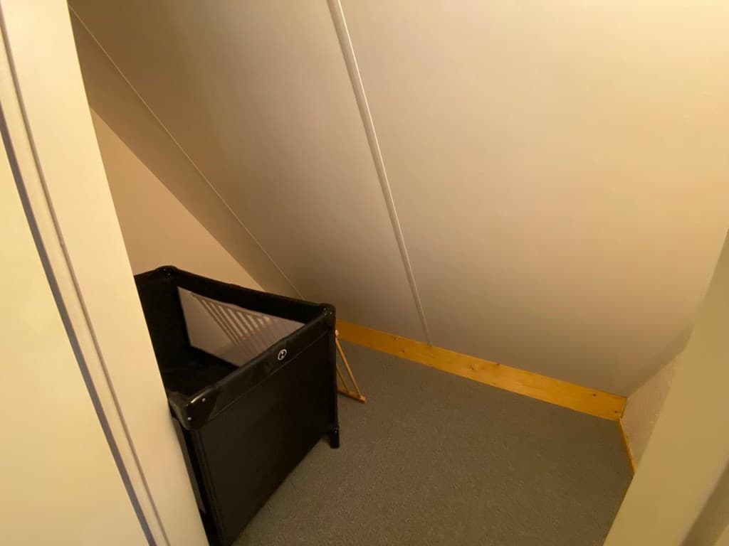 Een kleine ruimte met een trap en een opvouwbaar bedje in de hoek van een woning.