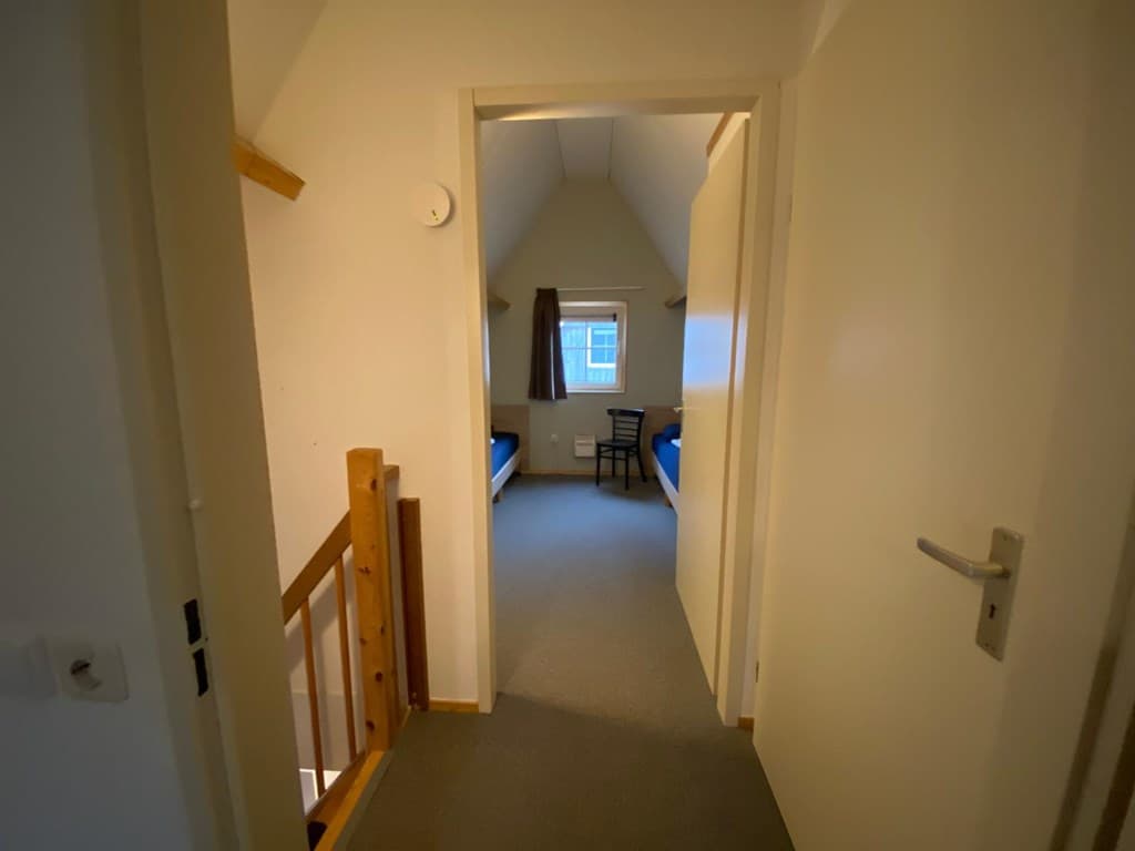 Overzicht van een gang met twee deuren naar slaapkamers en een trapleuning zichtbaar aan de linkerkant