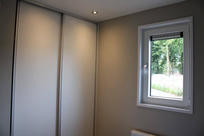 Sfeervolle slaapkamer met een raam en een inbouwkast met schuifdeuren