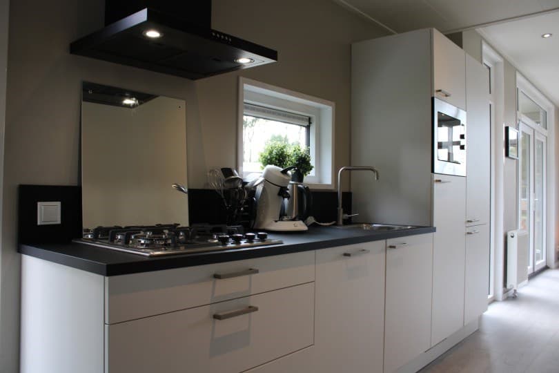 Moderne keuken met inbouwapparatuur, kookplaat, spoelbak en wandkast in lichte kleuren