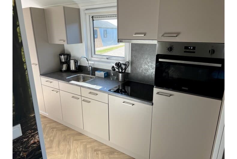 Moderne keuken met inbouwapparatuur, aanrecht en kasten in lichte kleuren, overzichtelijk en ruimtelijk ingericht