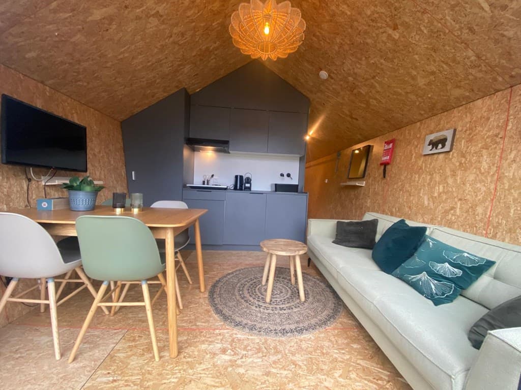 Interieur van een vakantiewoning met keuken, eettafel, zithoek en houten vloeren in EuroParcs De Zanding.