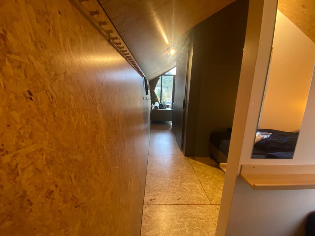 Gang met houten wand en zicht op een zithoek aan het einde van de verwarming in EuroParcs De Zanding, Otterlo