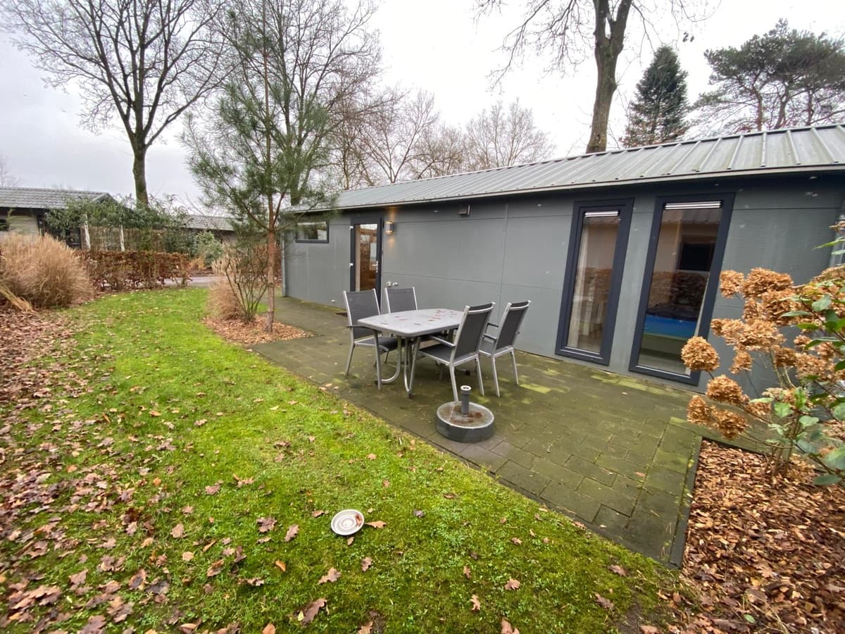 Moderne vakantiewoning met terras en zitgedeelte, omgeven door groen en bomen