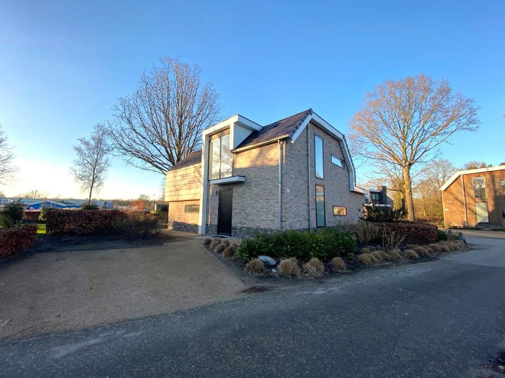 Moderne vakantiewoning met stenen gevel, grote ramen en een groene tuin bij EuroParcs Zuiderzee in Biddinghuizen