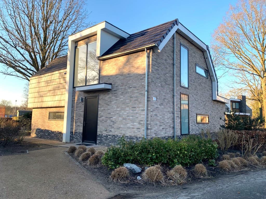 Moderne vakantiewoning met een stenen gevel, grote ramen en een aangelegde tuin in EuroParcs Zuiderzee, Biddinghuizen