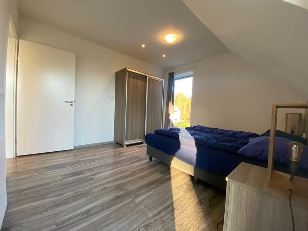Slaapkamer met een eenpersoonsbed, een kast en een raam met uitzicht op de buitenruimte.