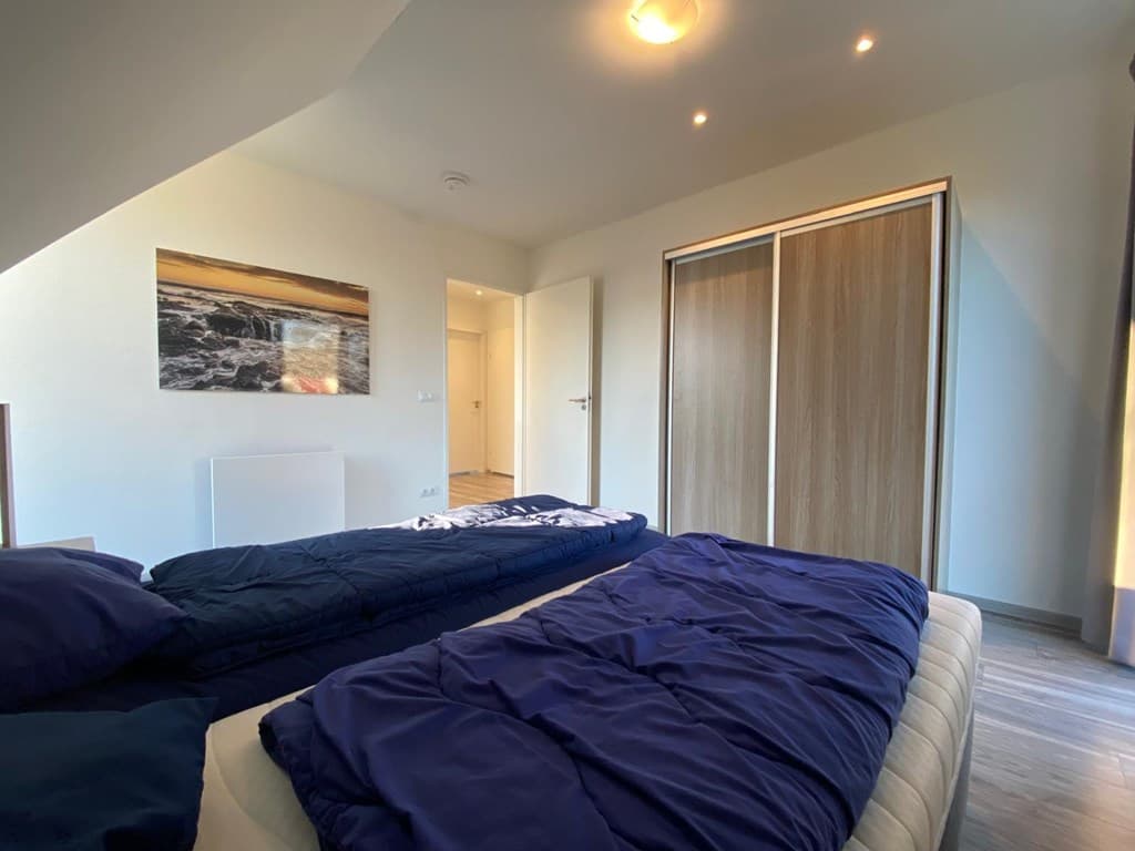 Slaapkamer met twee aparte bedden, grote kleerkast en deur naar een andere ruimte, met een raam en uitzicht op buiten.