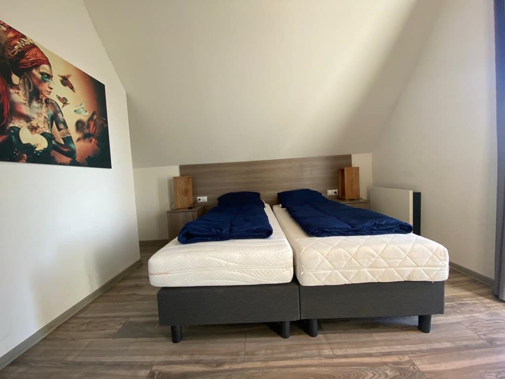 Slaapkamer met twee aparte bedden, nachtkastjes en een kunstwerk aan de muur