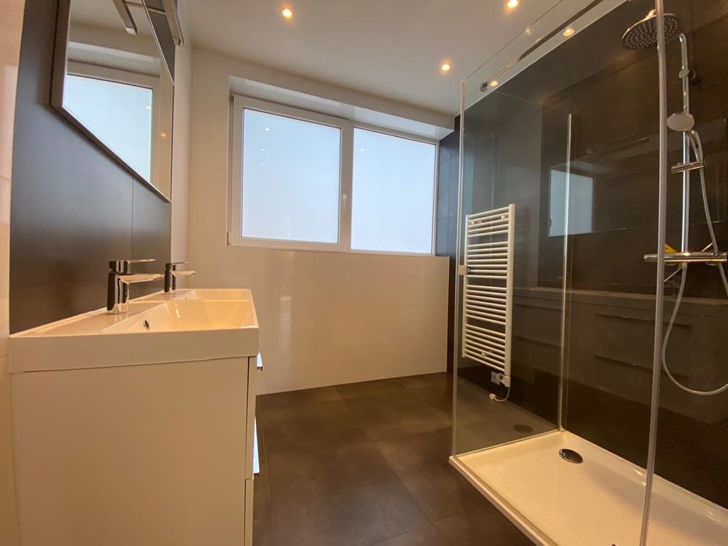 Moderne badkamer met douche, wastafel en grote ramen voor natuurlijk licht