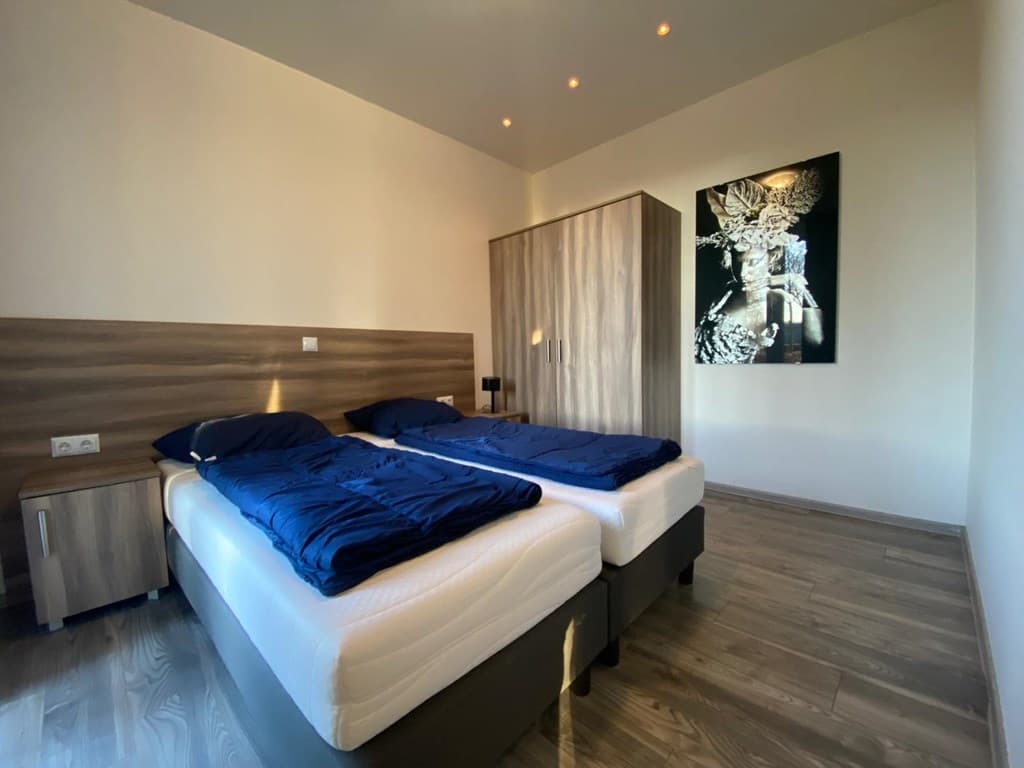 Slaapkamer met twee eenpersoonsbedden, houten meubelen en een decoratief schilderij aan de muur.
