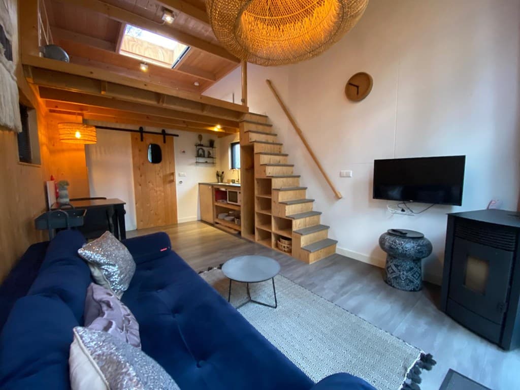 Gezellige woonkamer met houten elementen, trap, zithoek, tv en open keuken in EuroParcs Beekbergen.