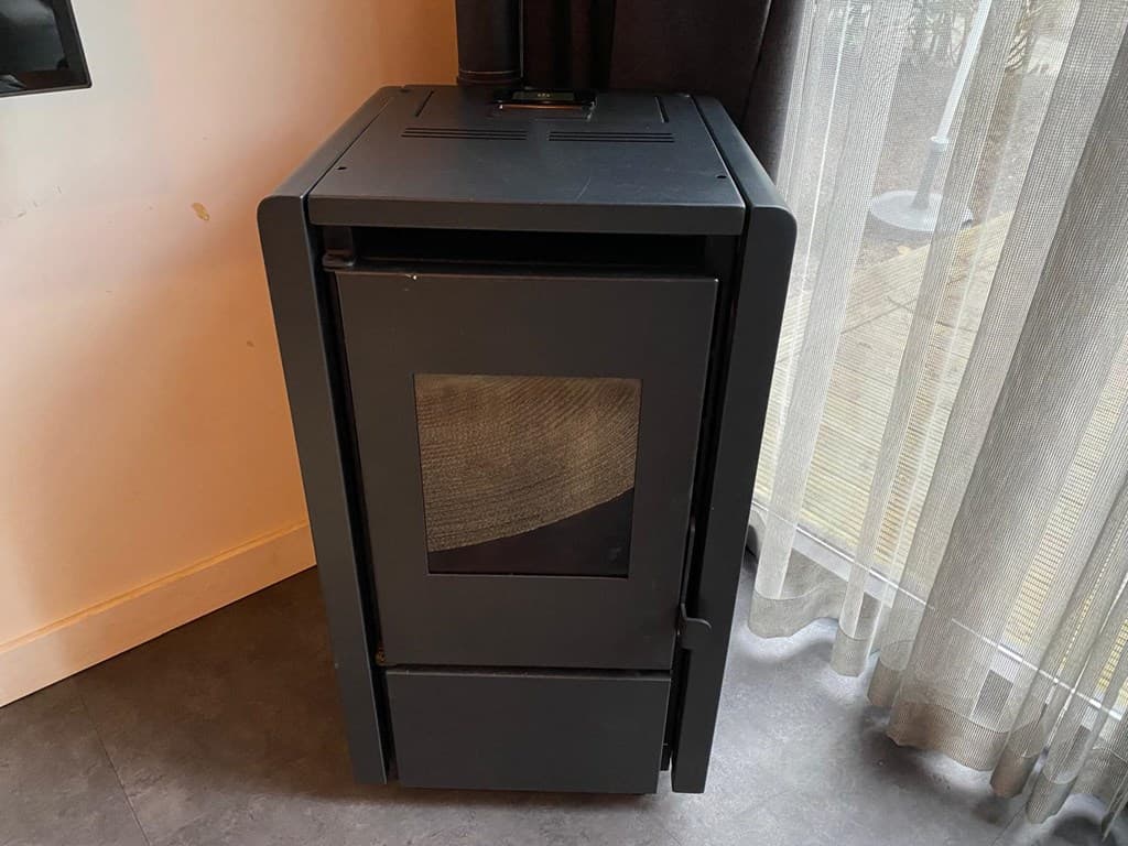 Zwart kacheltje staat naast een raam met gordijnen en heeft een glasvenster aan de voorkant.