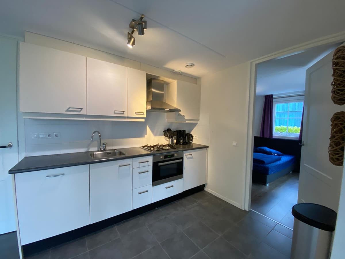Keuken met moderne apparatuur en werkblad, toegang tot woonkamer zichtbaar in de achtergrond