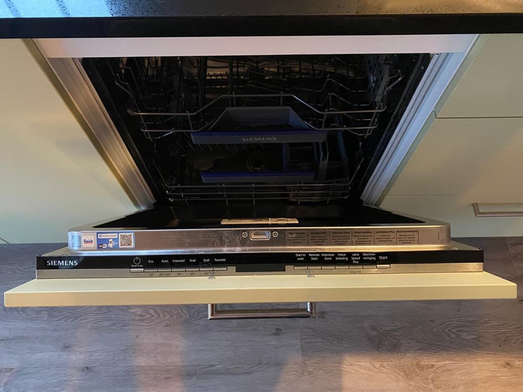 Inbouwvaatwasser met bedieningspaneel in een moderne keuken met opbergruimte en houten vloer.