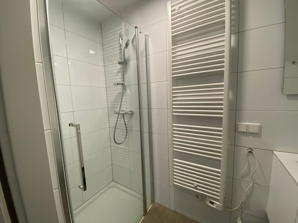 Moderne badkamer met inloopdouche, handdoekenradiator en wastafel met spiegel tegen de muur