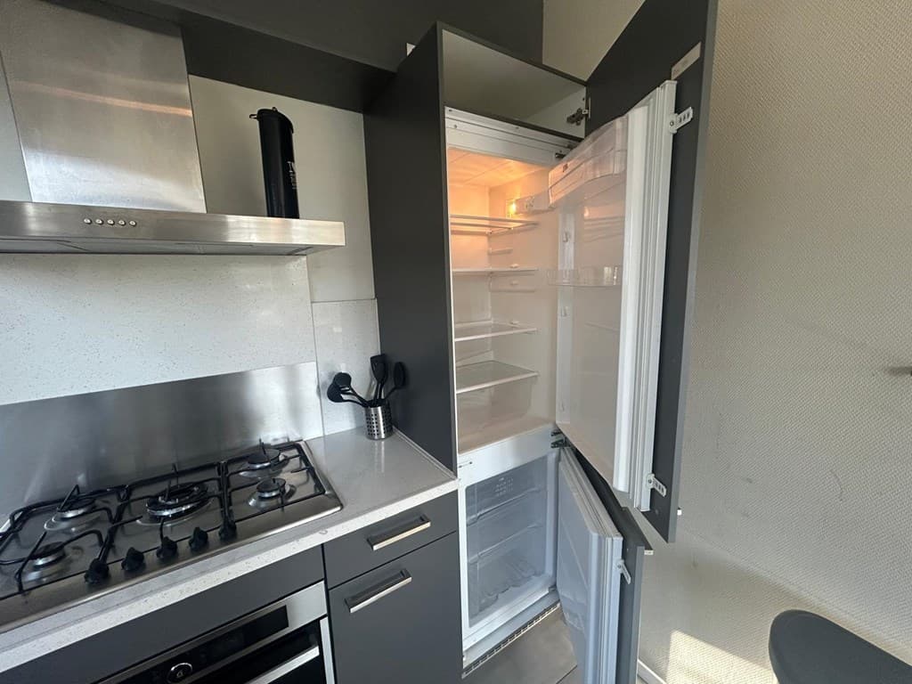 Moderne keuken met een open koelkast en een gasfornuis, in een sfeervolle ruimte met grijs en wit.