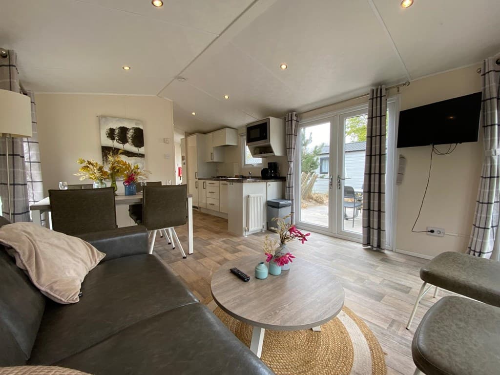 Moderne woonkamer met open keuken, eettafel en toegang tot een buitenruimte met tafels en stoelen