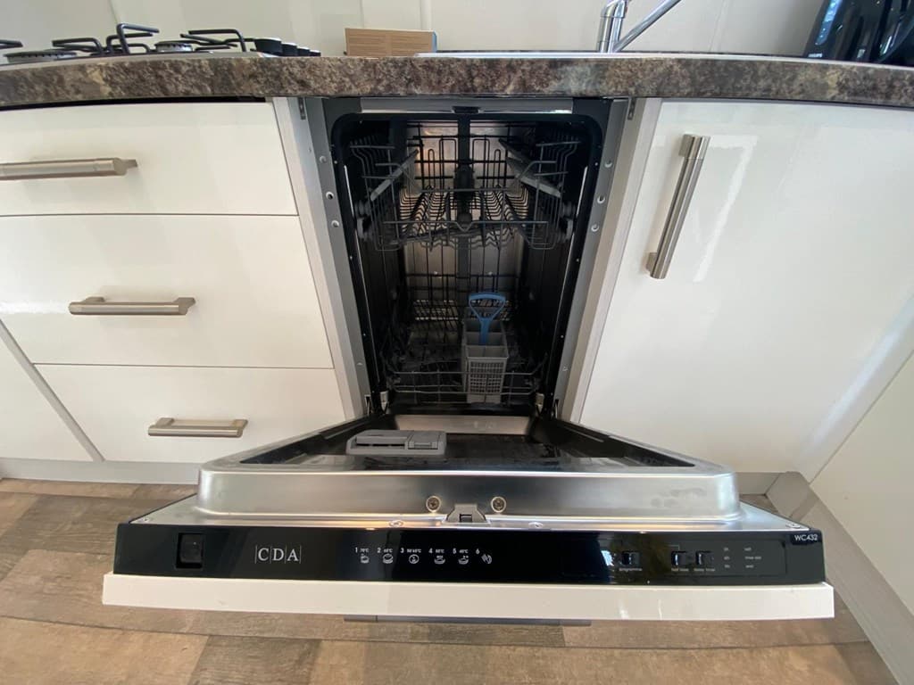 Inbouwvaatwasser met open deur in een moderne keuken met een granieten aanrechtblad.