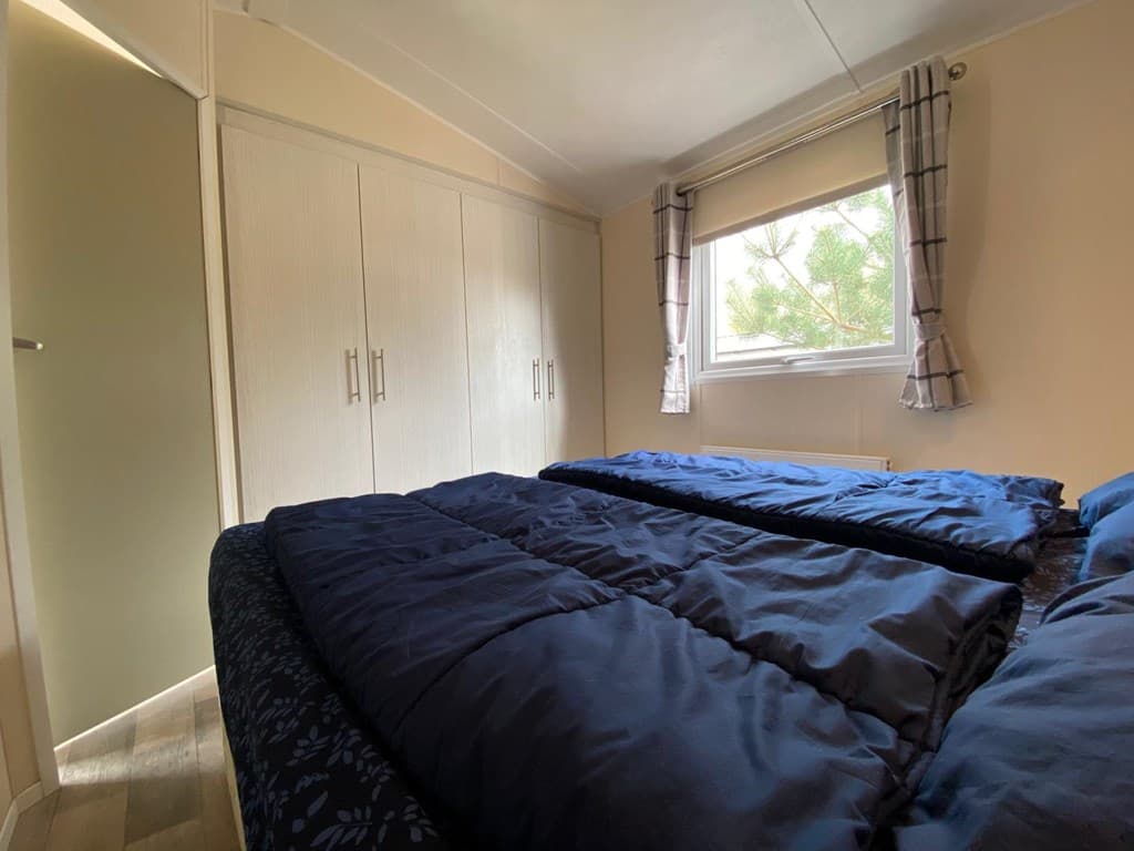 Slaapkamer met twee eenpersoonsbedden en een kledingkast, raam met uitzicht op buiten.