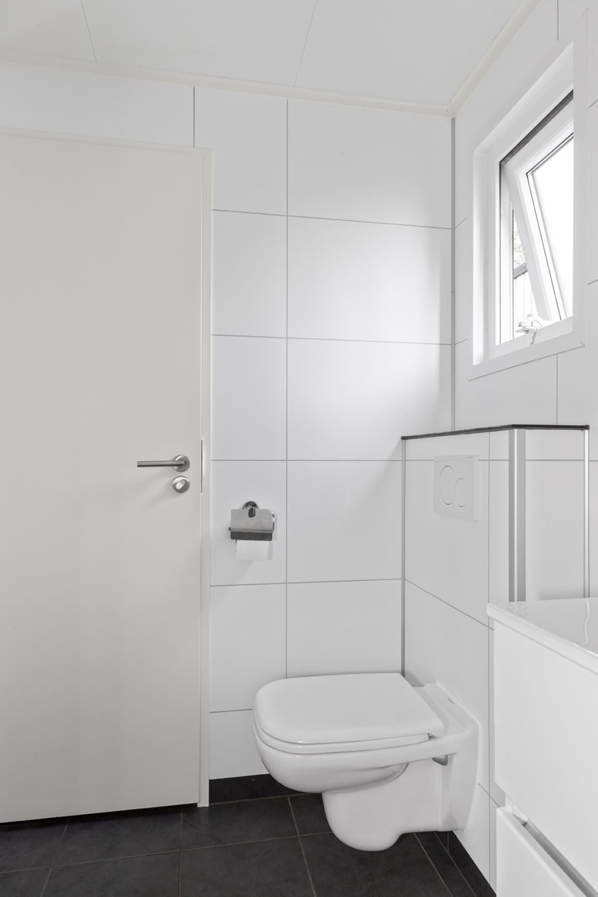 Witte badkamer met toilet, wastafelmeubel en raam voor natuurlijk licht
