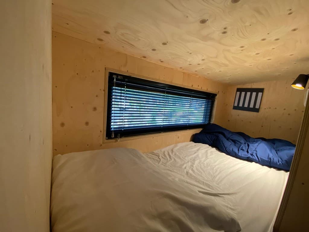 Slaapruimte met stapelbed en houten wandafwerking, verduisterende jaloezieën en een raam voor natuurlijk licht