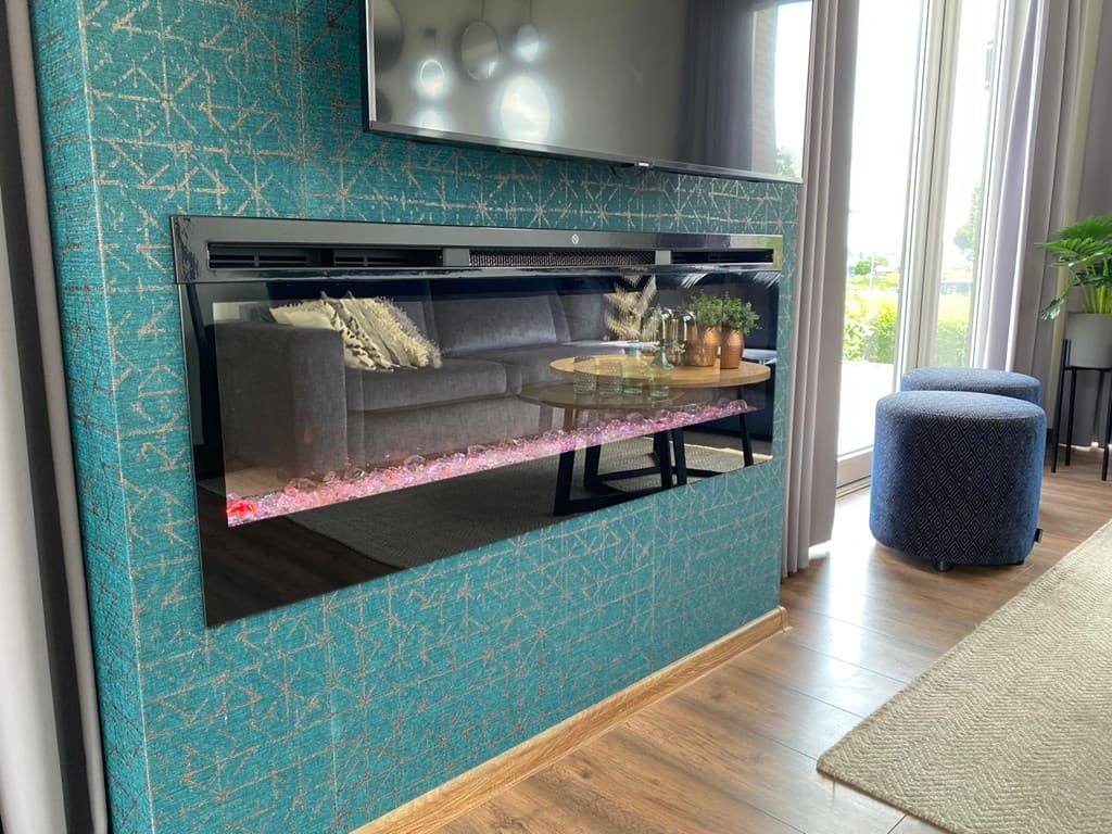 Moderne woonkamer met een wandhaard, stoffen bank, salontafel en grote ramen die uitzicht bieden op buiten.