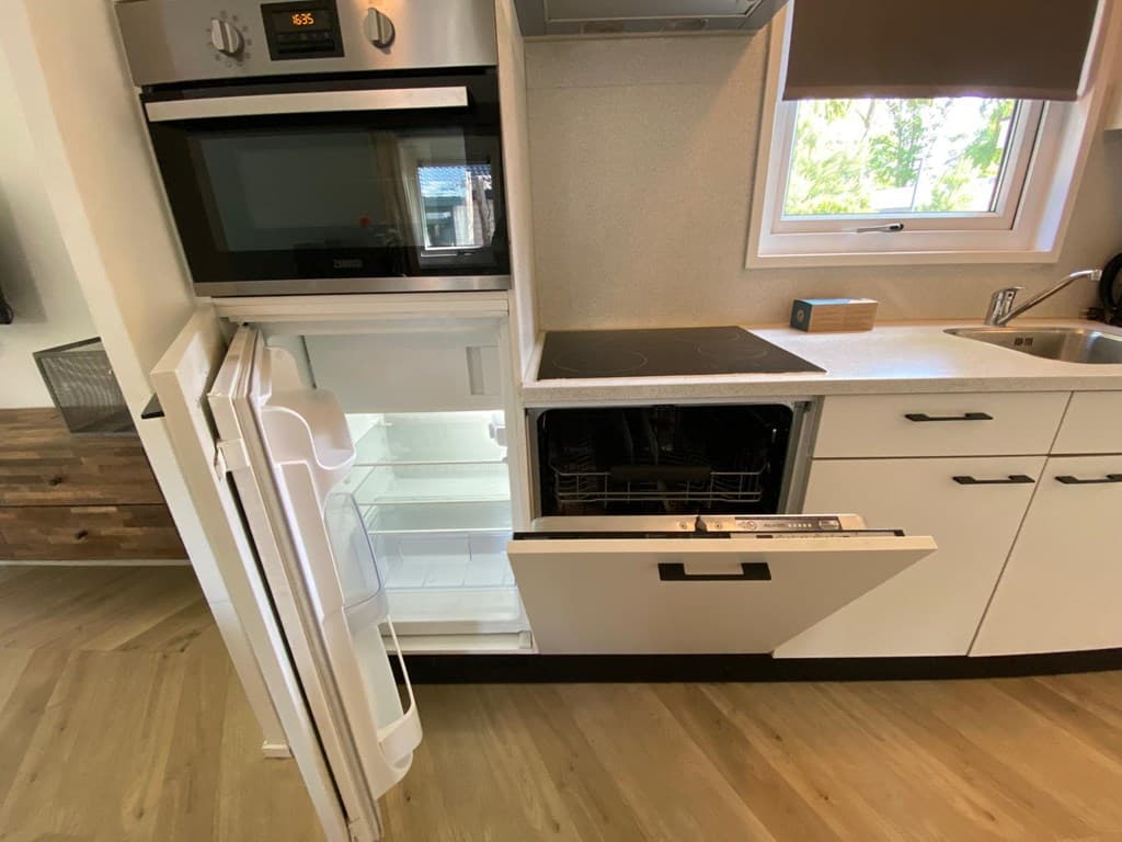 Ingerichte keuken met een oven, koelkast en vaatwasser in een moderne stijl.