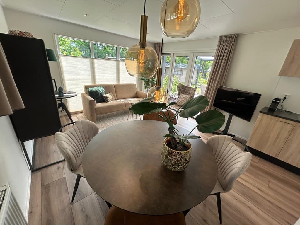 In de woning is een moderne eetkamer met een ronde tafel en stijlvolle stoelen, een zithoek en grote ramen met veel licht.