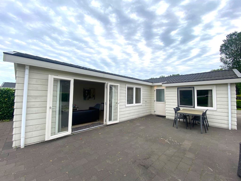 Moderne vakantiewoning met ruime terrasschermen en uitzicht op een betegelde patio in EuroParcs Spaarnwoude.