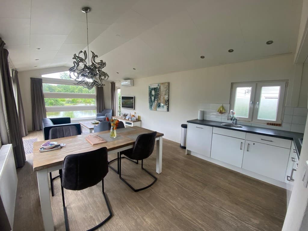 Moderne woonkamer met open keuken, eettafel en comfortabel zitgedeelte bij EuroParcs Spaarnwoude.