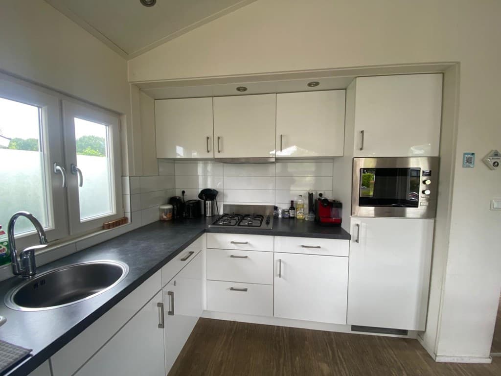 Moderne keuken met witte kasten, zwart aanrechtblad en inbouwapparatuur zoals een oven en kookplaat