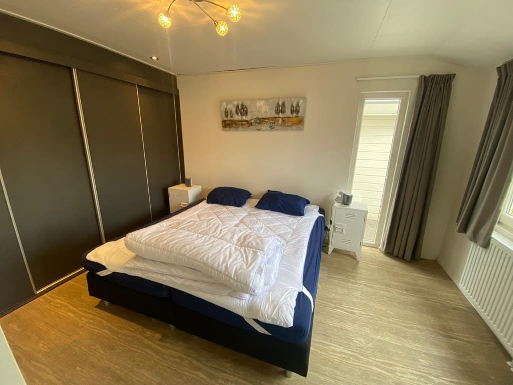 Slaapkamer met een groot bed, een kastwand, nachtkastjes en een raam met uitzicht naar buiten.